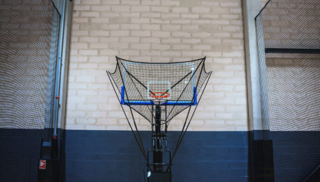 Automated basketball shooting machine in an indoor court, showcasing advanced basketball training technology for skill development and efficiency.