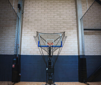Automated basketball shooting machine in an indoor court, showcasing advanced basketball training technology for skill development and efficiency.