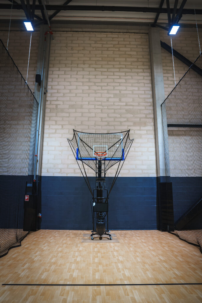 Automated basketball shooting machine in an indoor court, showcasing advanced basketball training technology for skill development and efficiency.
