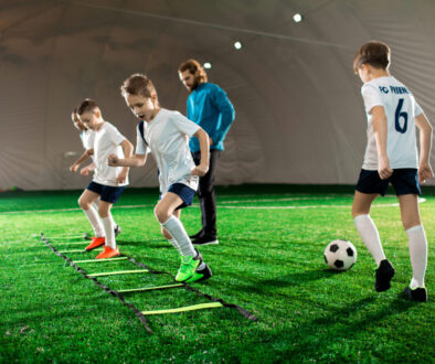 A busy soccer training facility with players practicing drills and coaches providing guidance, illustrating the essentials of running a well-organized program and offering insights into how to start a soccer training business.