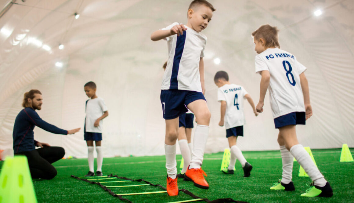 Soccer academy business plan concept showing a team of several boys training on a green pitch before a game or competition.