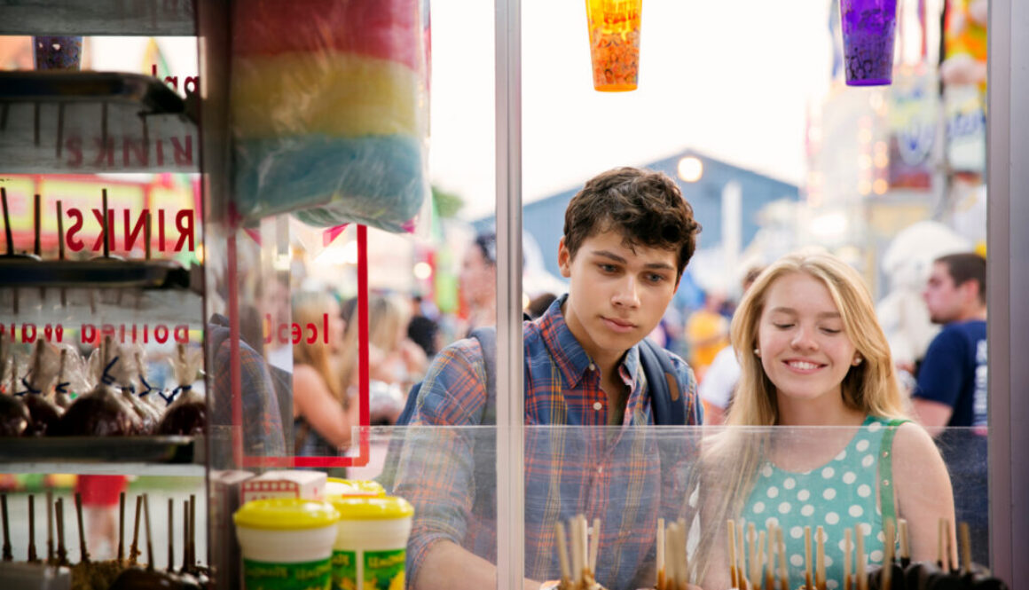 Couple looking at chocolate lollipops while standing in amusement park
