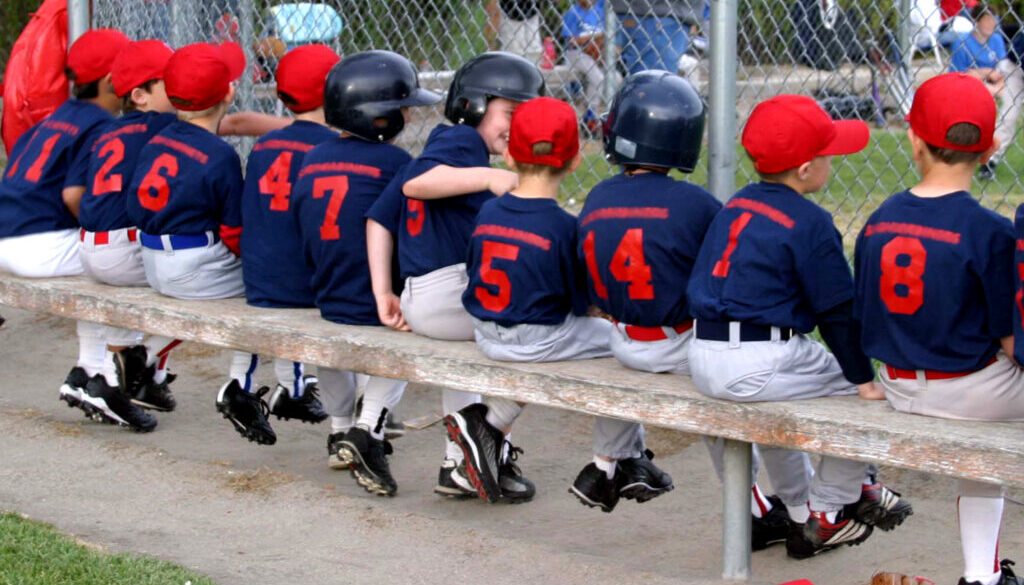 Youth baseball team on the bench during a game, highlighting the importance of baseball team management