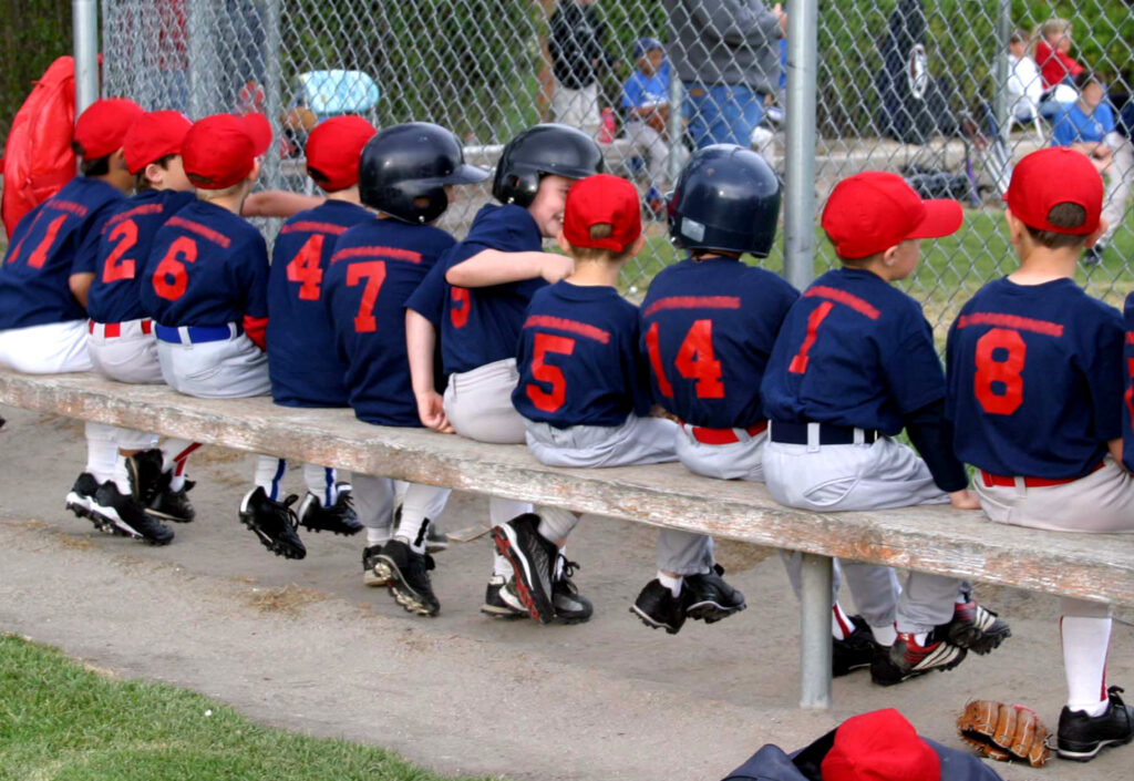 Youth baseball team on the bench during a game, highlighting the importance of baseball team management