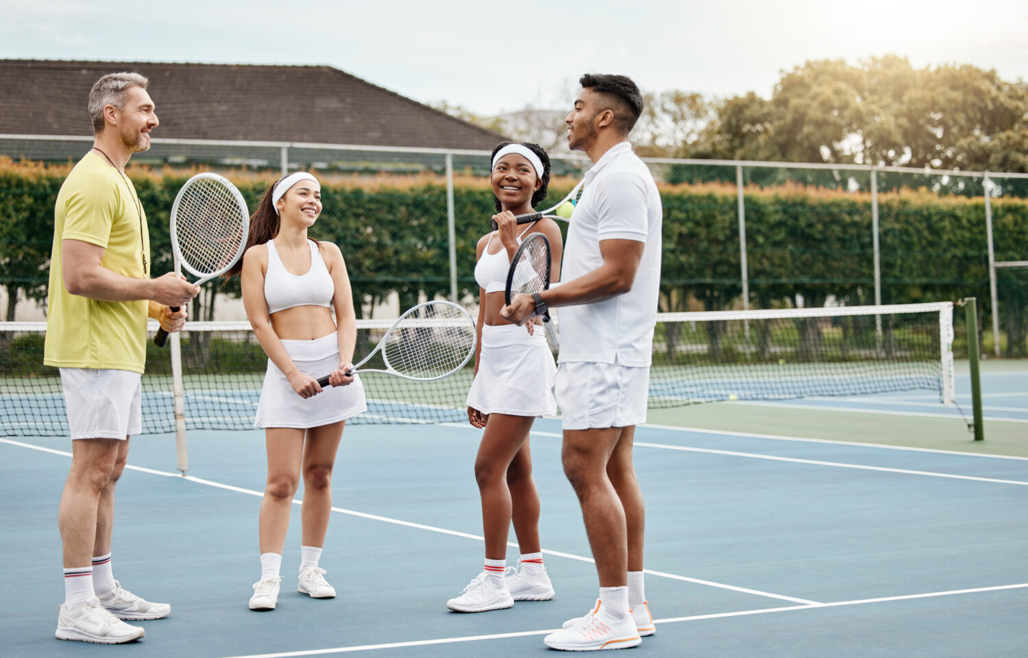 Tennis coach speaking to students on an outdoor court, highlighting how tennis club management coordinates schedules for players