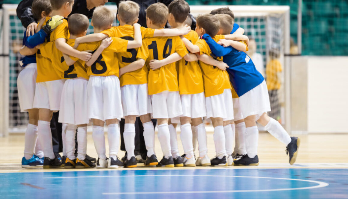 Young soccer players gather in a close huddle on an indoor court. It is an example of the team model from the different facility management models