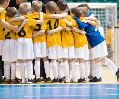 Young soccer players gather in a close huddle on an indoor court. It is an example of the team model from the different facility management models