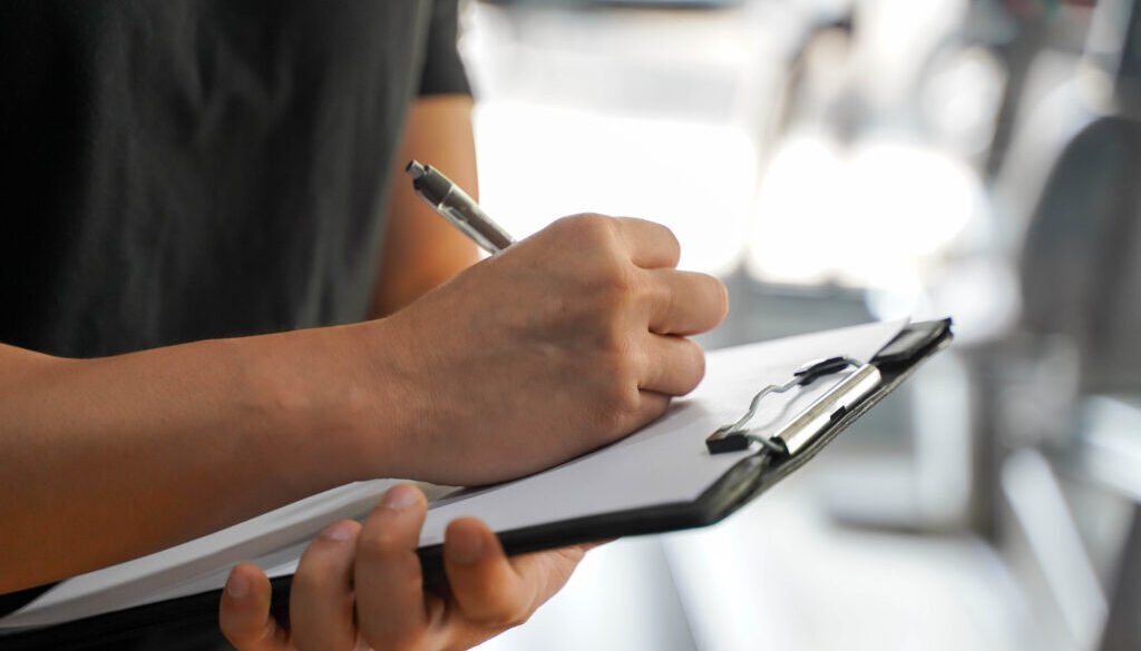 Closeup Asian young officer of the gym and fitness trainer checking fitness equipment maintenance list at fitness center.