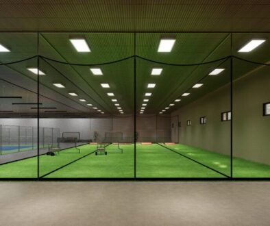 Modern multi-sport indoor facility with turf fields and hard courts for baseball, softball, and tennis training.