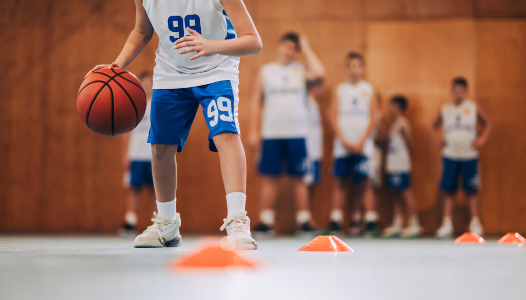 Youth basketball player practicing ball handling drills during a training session, which is a common starting point for basketball training businesses.